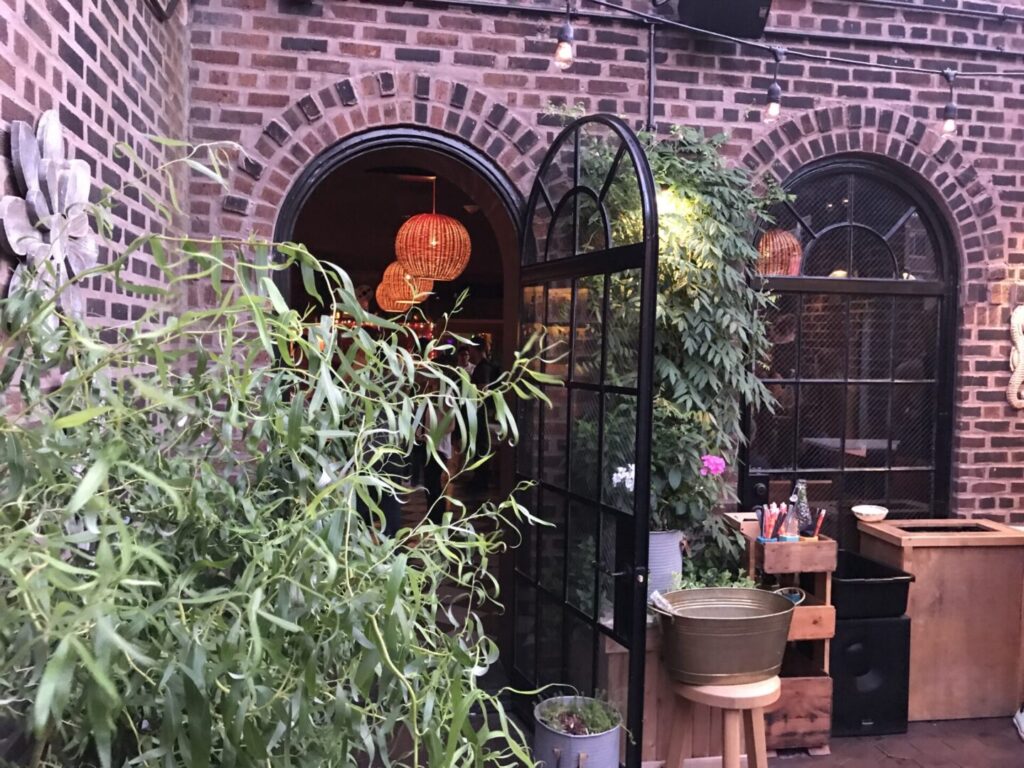 A brick building with plants growing in the corner.