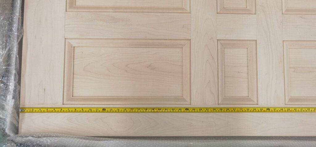 A wooden door with a yellow measuring tape on it.