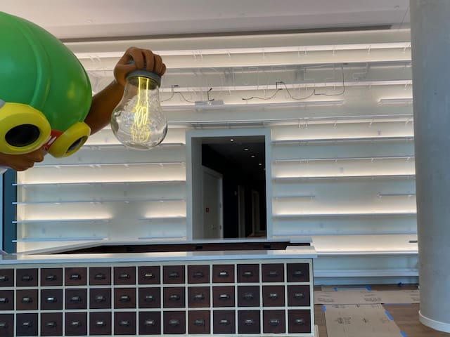 Person installing a clear light bulb on an exterior wall.