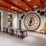 A room with a large clock and a giraffe.