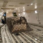 A cargo train with a cage on the side of it.