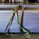A pair of green and brown leashes hanging on the side of a building.