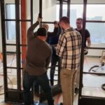 A group of people standing around in front of windows.