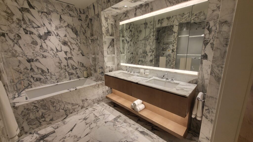 Luxurious marble bathroom with elegant lighting and wooden accents.