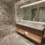 Luxurious marble bathroom with elegant lighting and wooden accents.