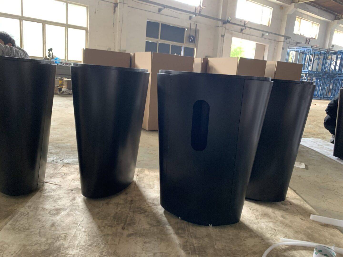 A group of black trash cans sitting on top of a floor.
