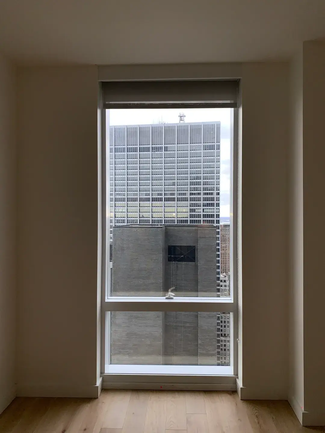 A window with blinds in the corner of an empty room.